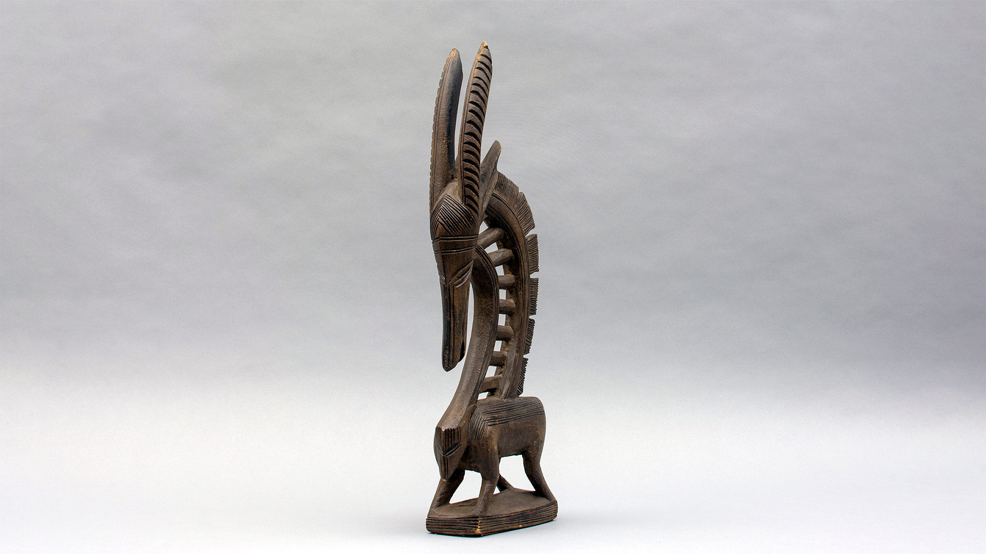 photograph of abstract wooden antelope shaped carving, showing the figure at an angle