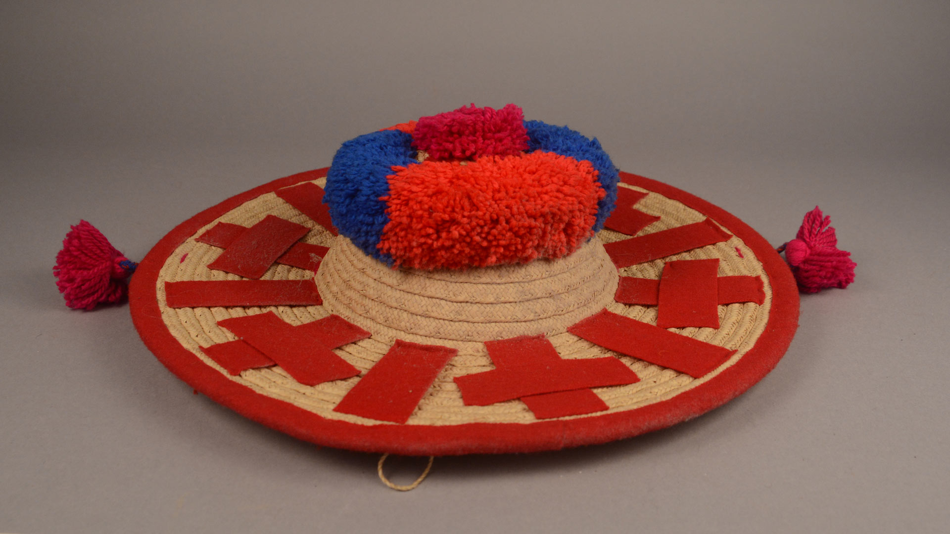 sombrero-style hat with a red trim and red and blue puffs on the top