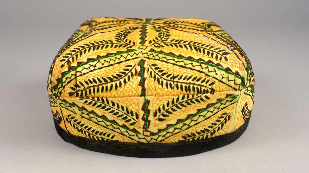round yellow hat with a black trim and decorative embroidery in brown, yellow, green, and black