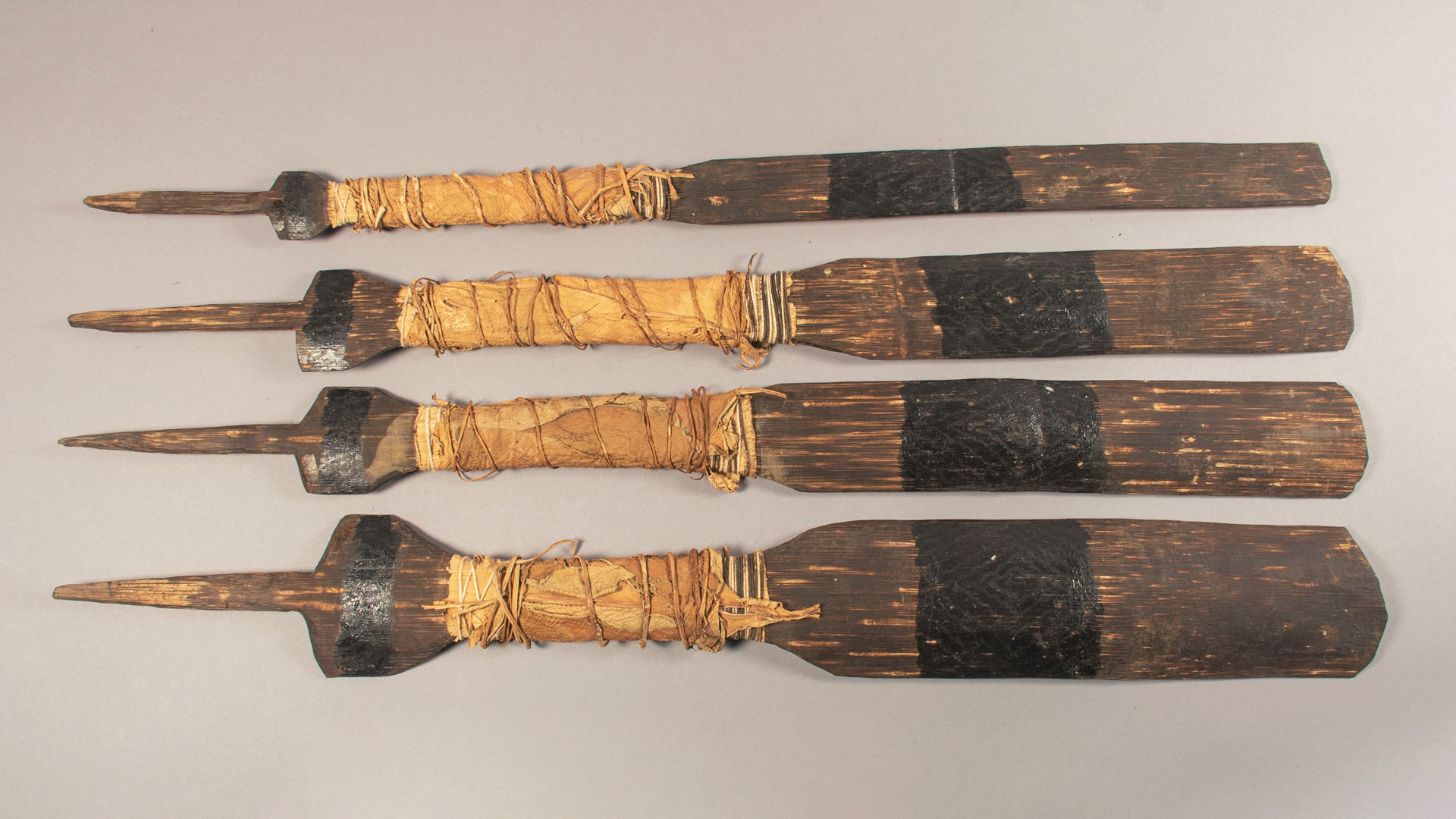four dark brown wooden paddles arranged from smallest paddle to largest paddle 