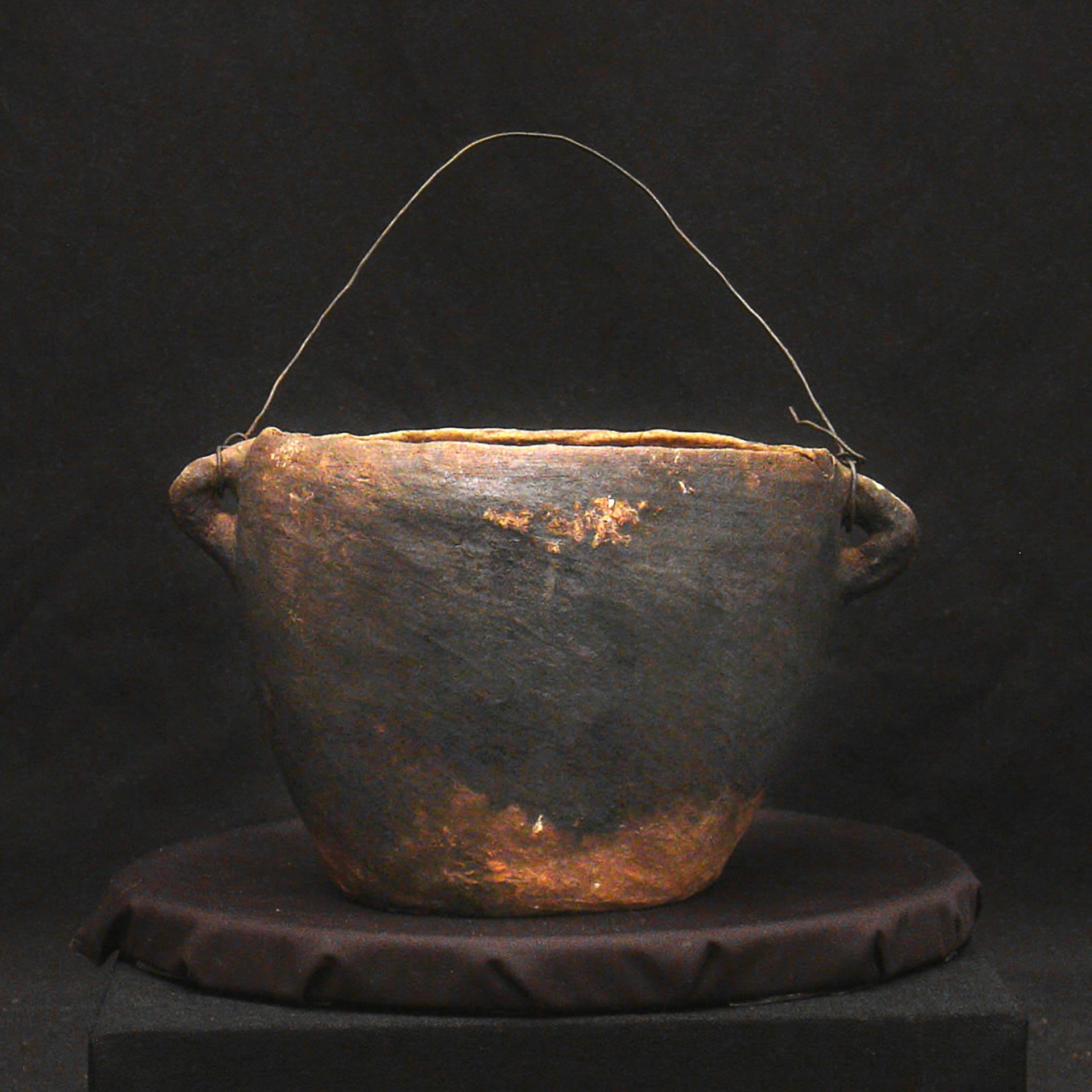 black and brown clay pot with a metal wire handle
