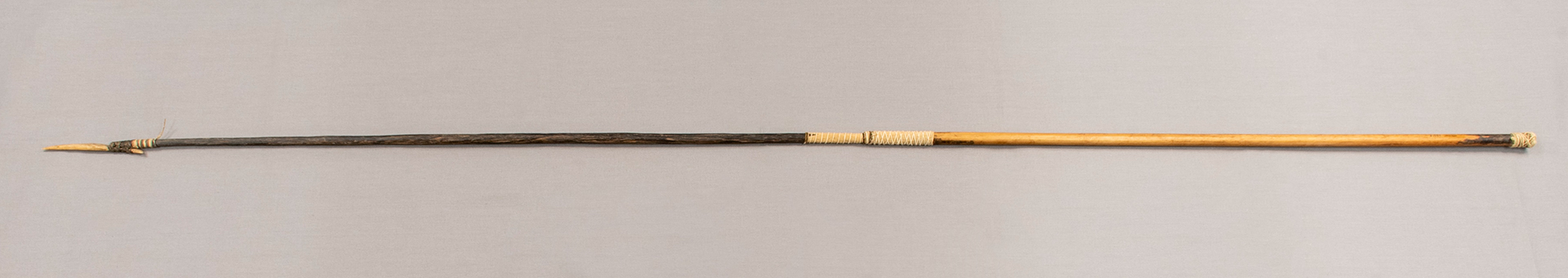 dark brown wooden arrow with a tip made from a sharpened piece of bone