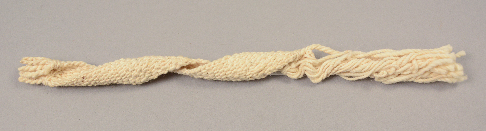 woven strip of white yarn with frayed edges