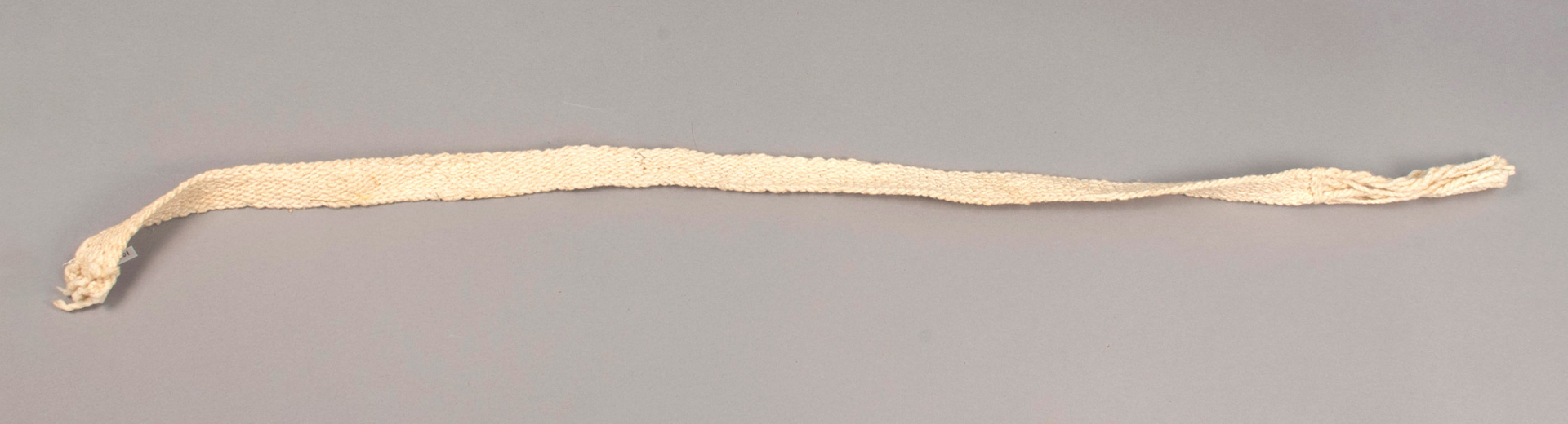 long woven strip of white yarn with frayed edges