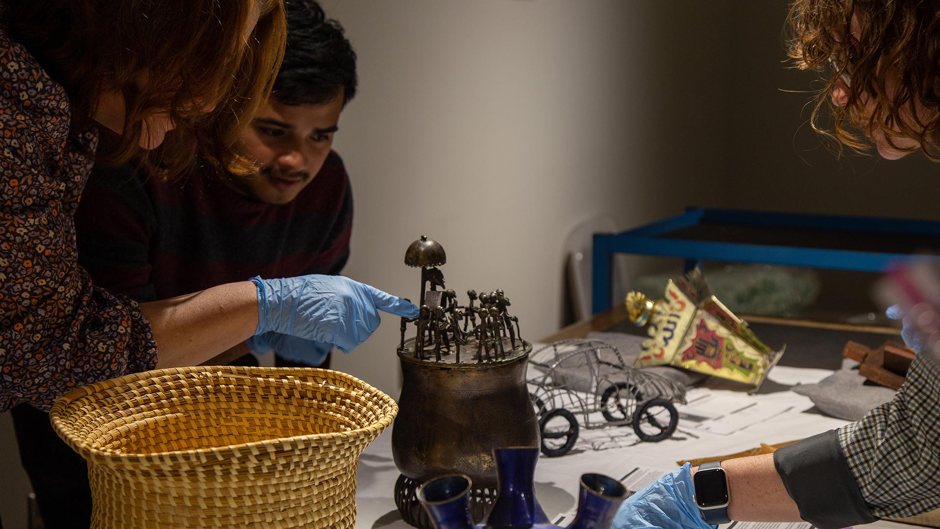 musuem staff pointing and assessing a metal artifact