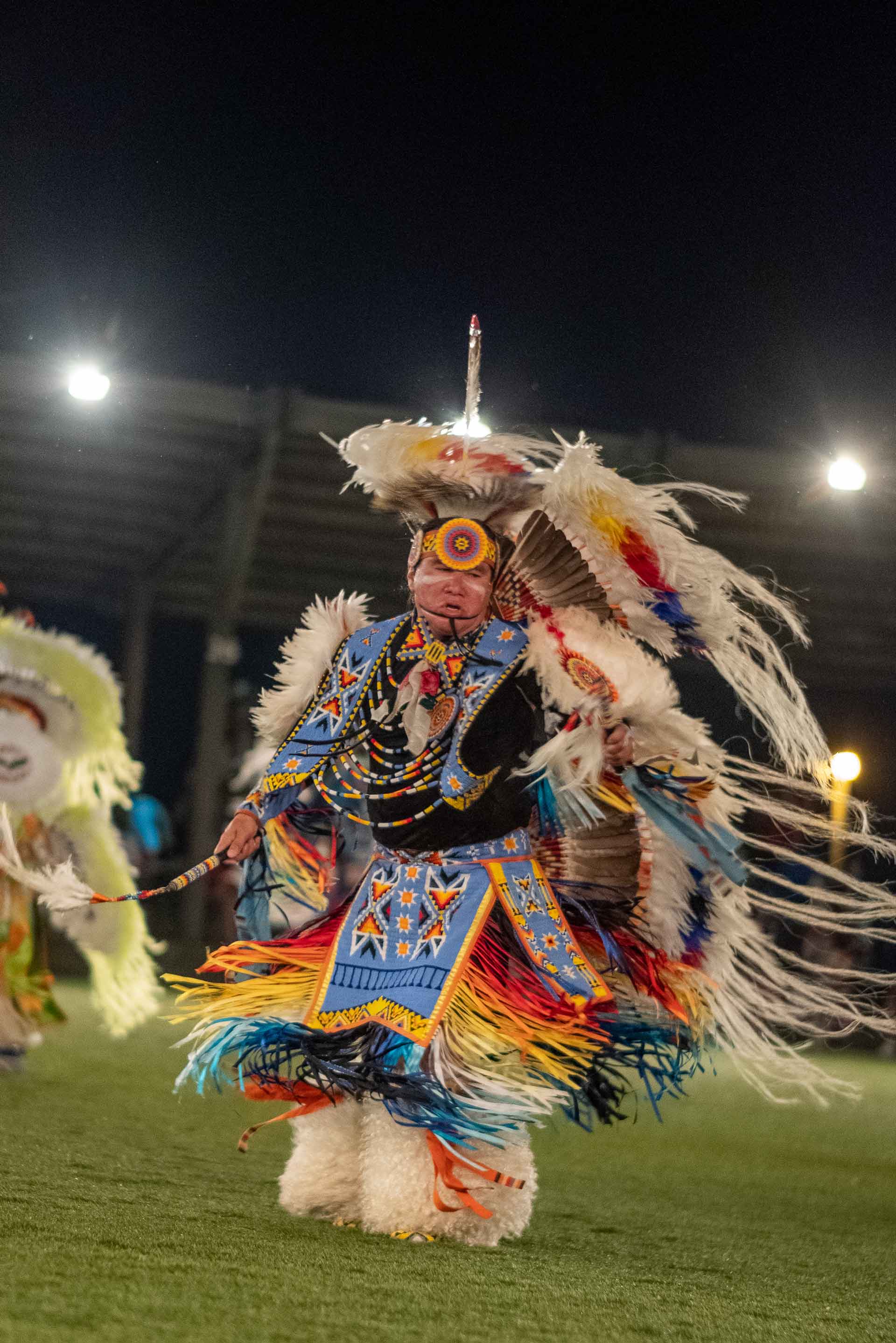 older Native American man dancing wearing clothing with lots of feathers