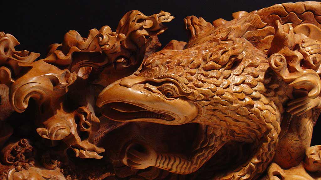 A close up of a brown carved wooden figurine of the eagle Jatayu
