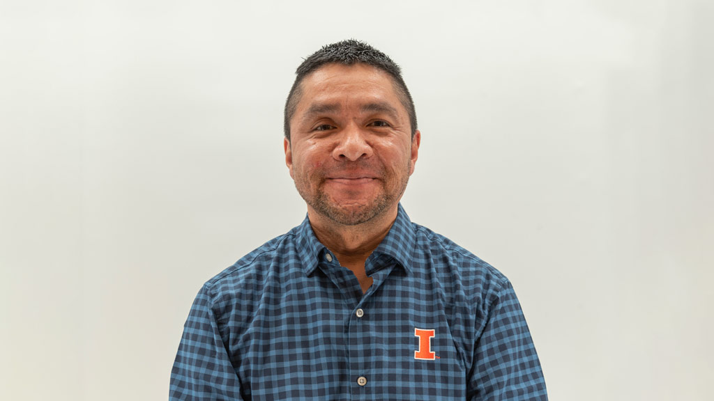 Jimmy Gonzalez smiling and wearing a blue flannel, on a white background