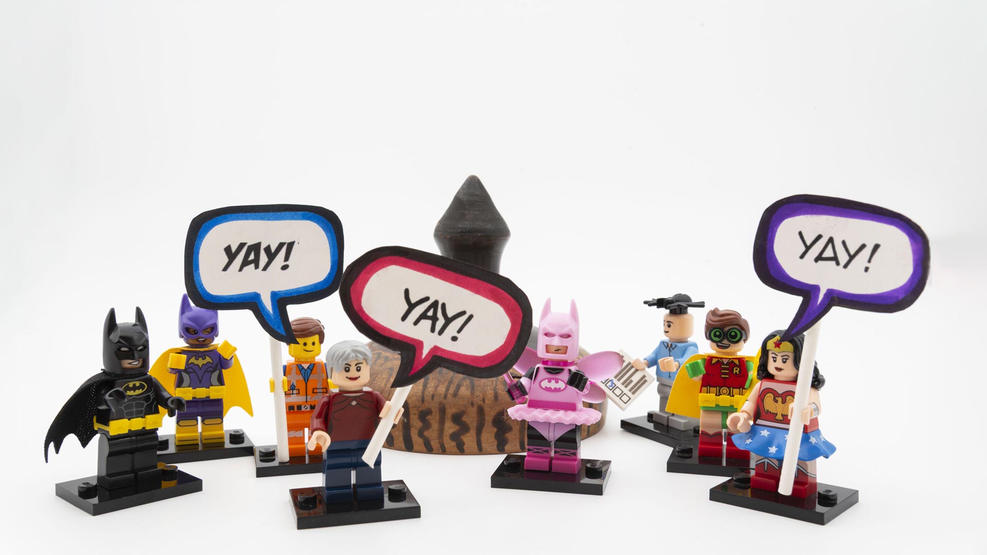 8 LEGO figures pose with YAY signs in front of a repaired object.