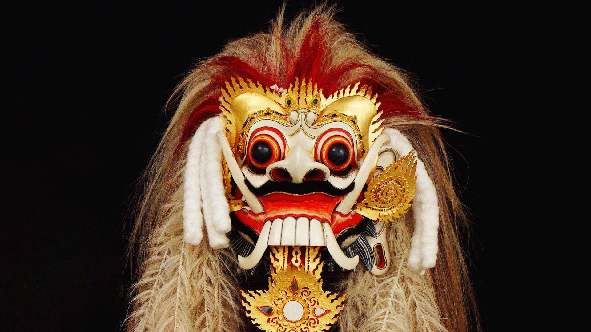 A close up view of the front of a mask with long tusk and fur hair