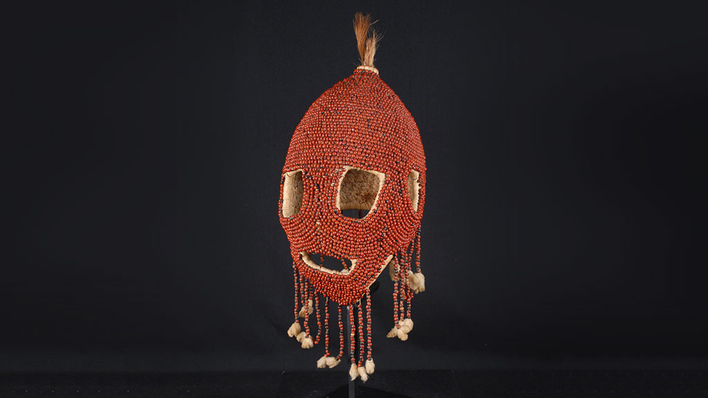 red beaded head-shaped mask with large eye and mouth holes