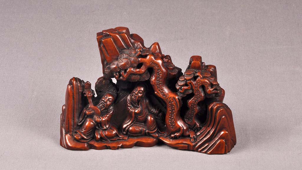 carved brush rest with two men under a tree near mountains