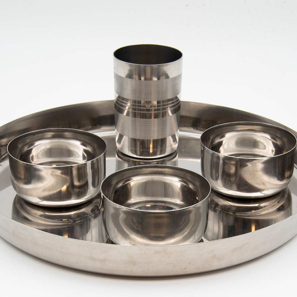 A stainless steel plate with three bowls and a tall cup on a light gray background