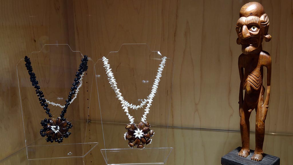 a case with two similar necklaces with different colors and a small statue