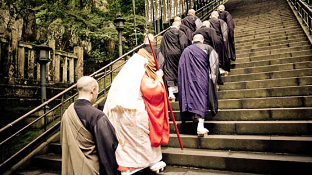 Promotional photo: monks proceeding up stone stairs to a temple