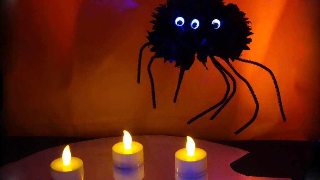 Spider craft hanging over a spooky setting of candles and mirrors