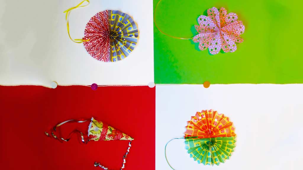 Four paper crafts made with colorful geometric designed paper and ribbons.