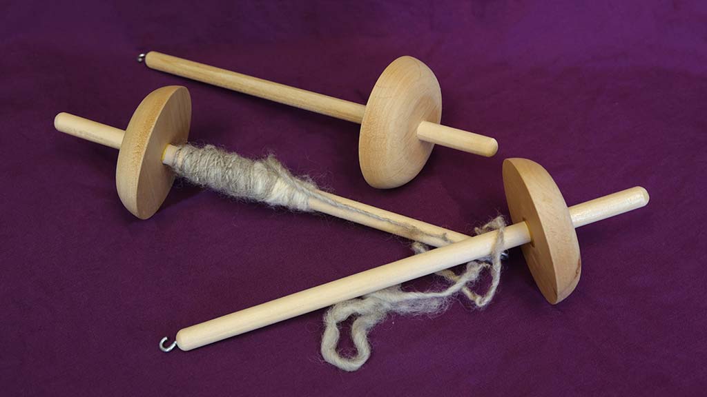 3 wooden drop spindles, one with yarn