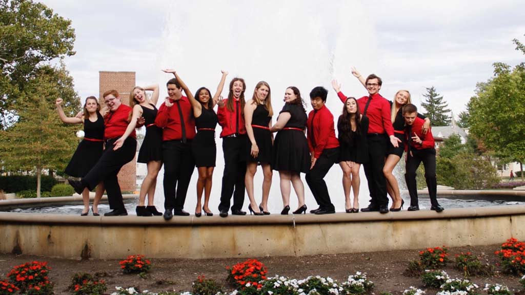 Acapella group posing outdoors on fountain.