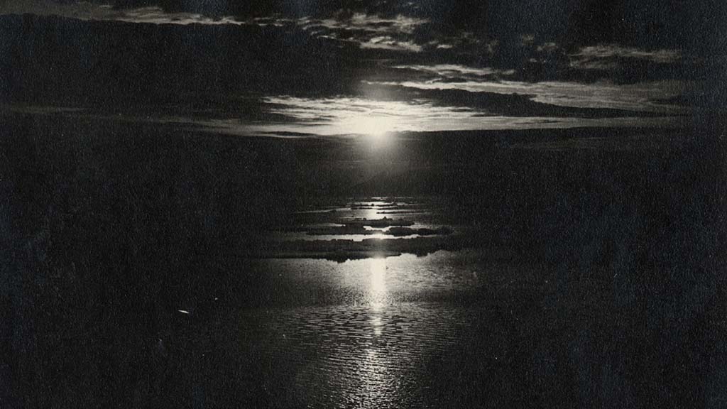 black and white photo of a sunset viewed high above arctic waters