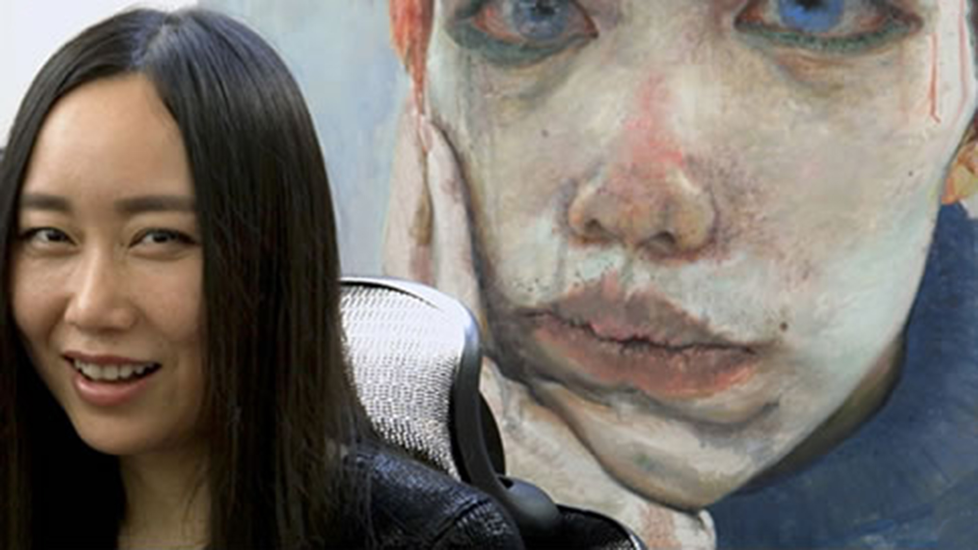 A lady sits in a chair in front of a large painting of a girl resting her head on the palm of her hand