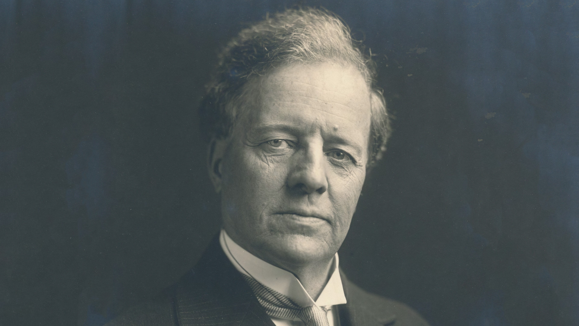 Portrait shot of Edmond James in a suit looking at the camera