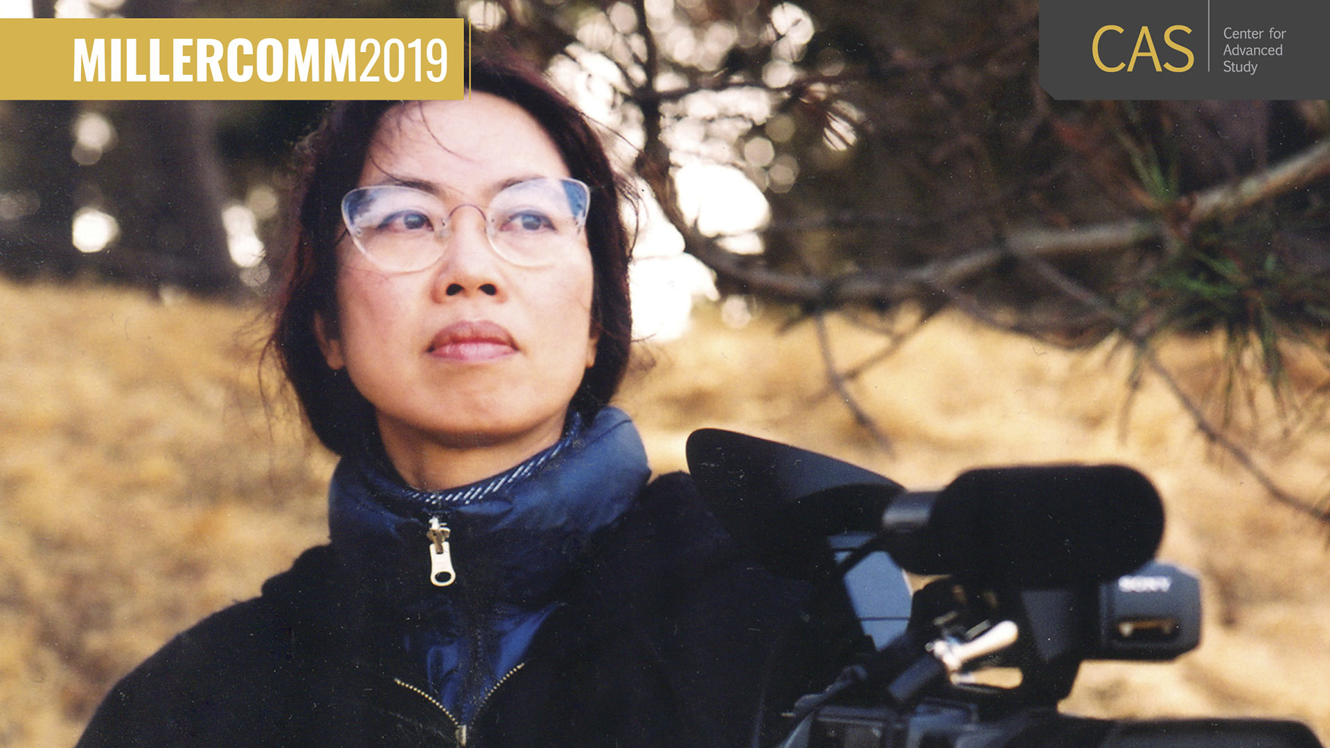 A woman with glasses from Asian descent stands outside in cool weather and gazes off camera