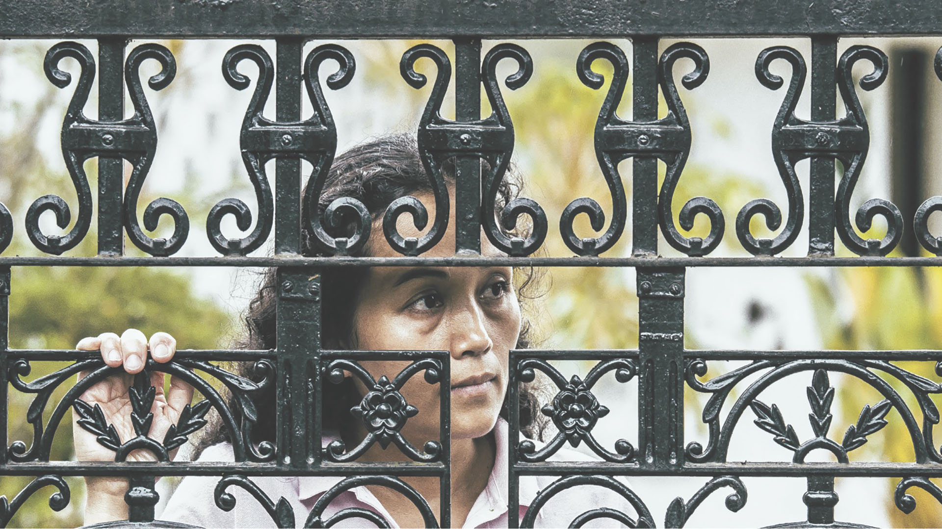 woman staring through black fence