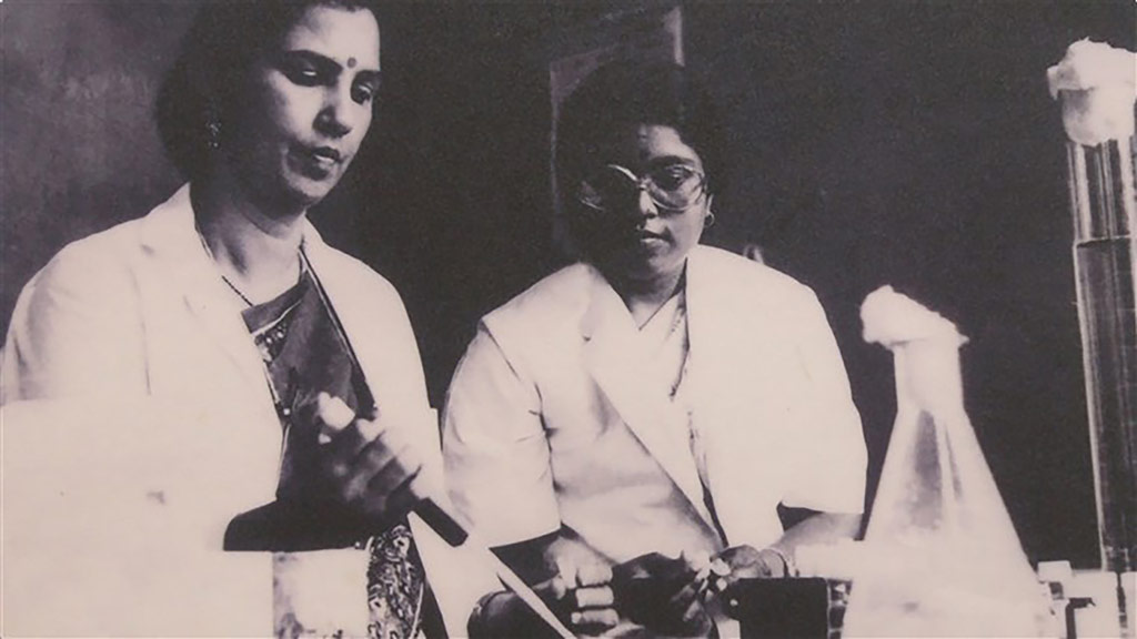vintage photo of two Indian women in lab coats performing an experiment