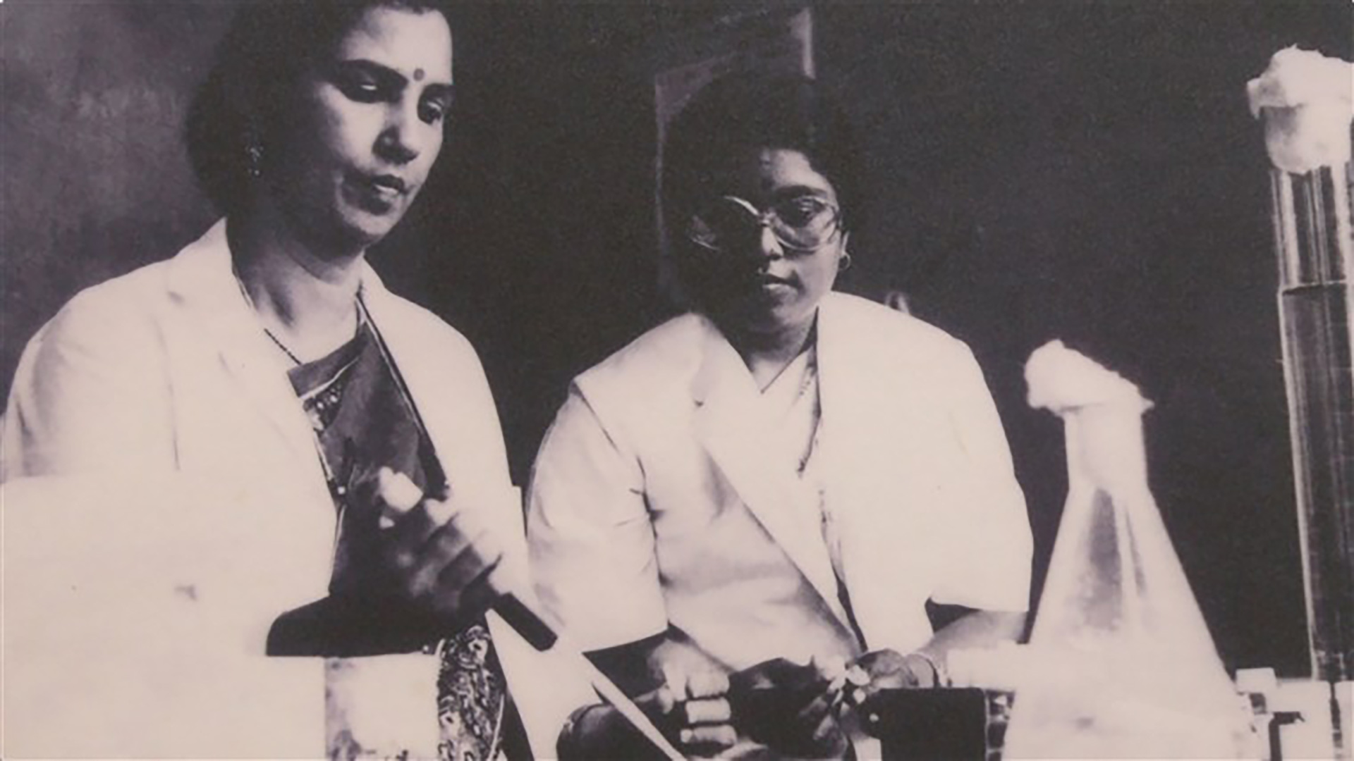 vintage photo of two Indian women in lab coats performing an experiment