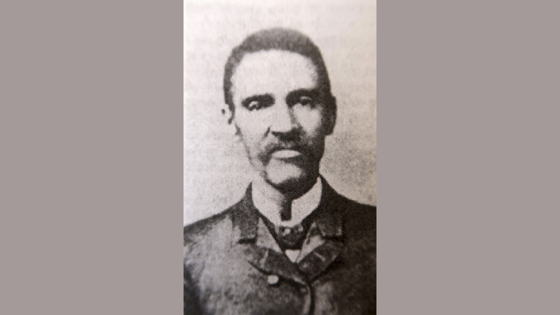 vintage black and white studio portrait of a man with white collar and dark jacket