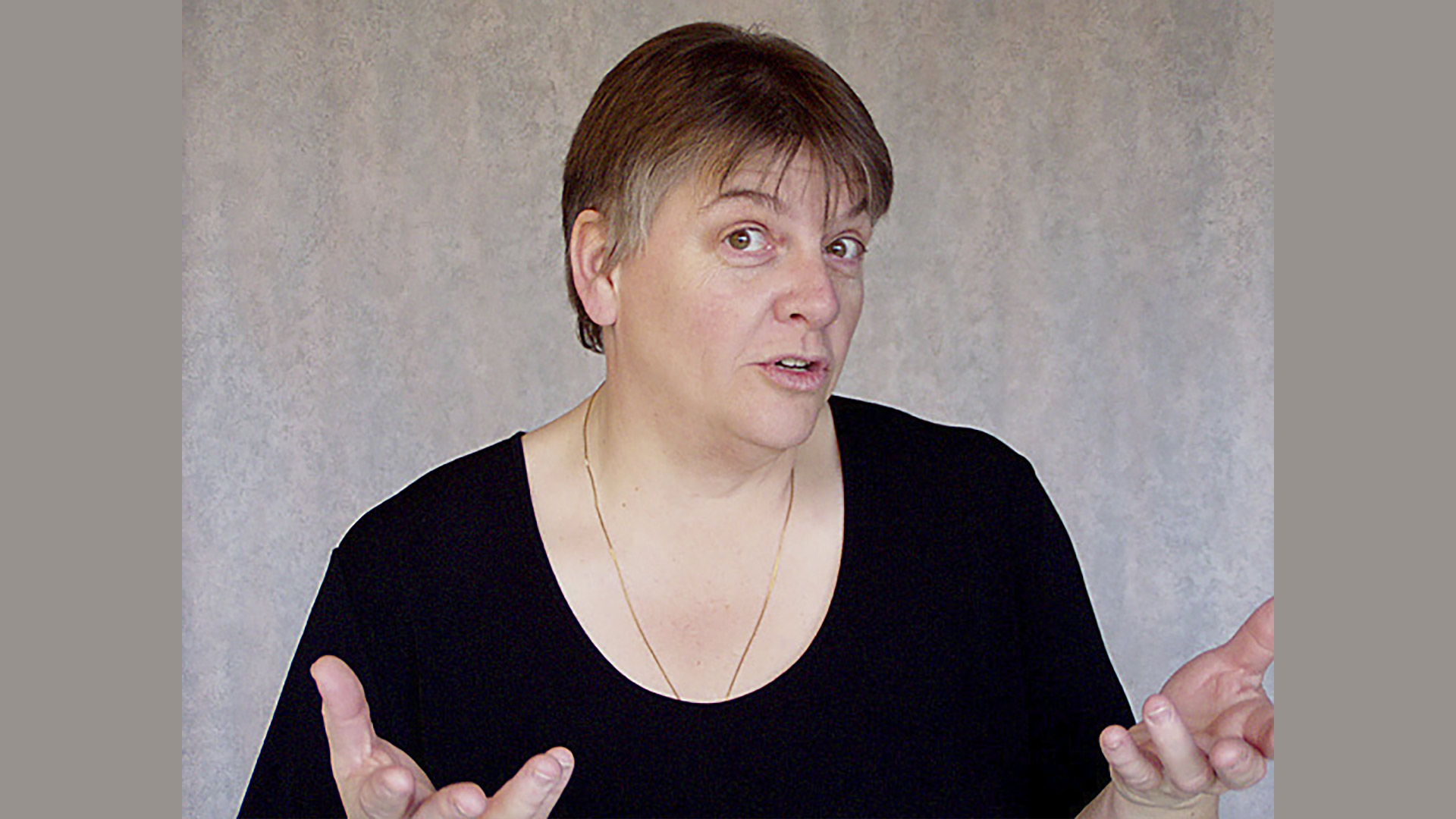 studio shot of woman in black shirt posing with hands out and palms up