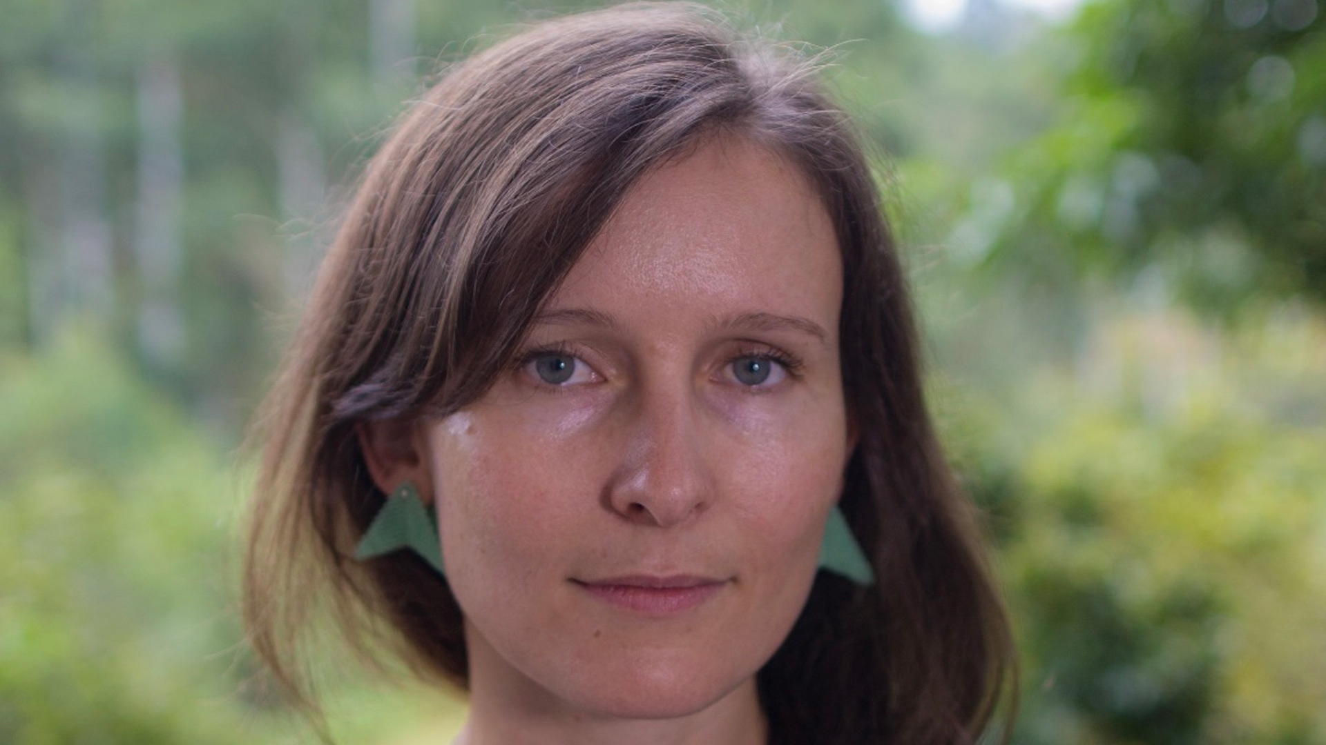 Woman smiling stoically with trees in background