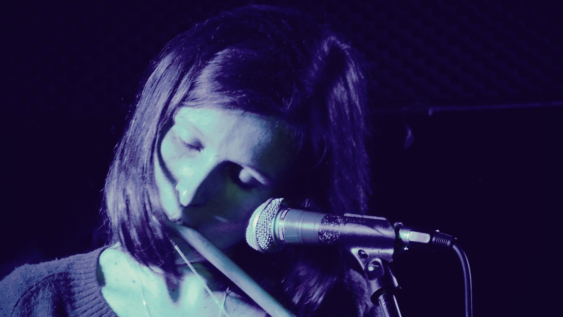 woman playing instrument in front of microphone