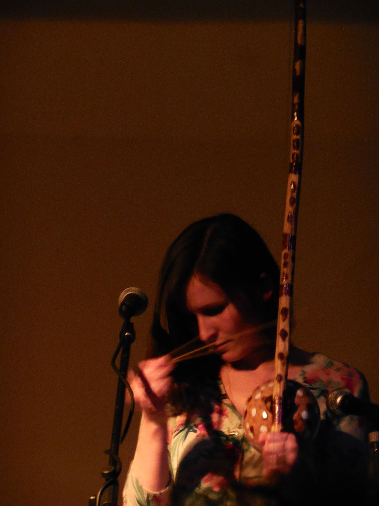 woman playing wooden, indigenous instrument in front of microphone