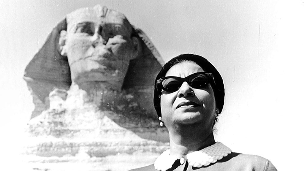 Vintage photo of woman with glasses poses in front of an image of the Sphinx in Egypt