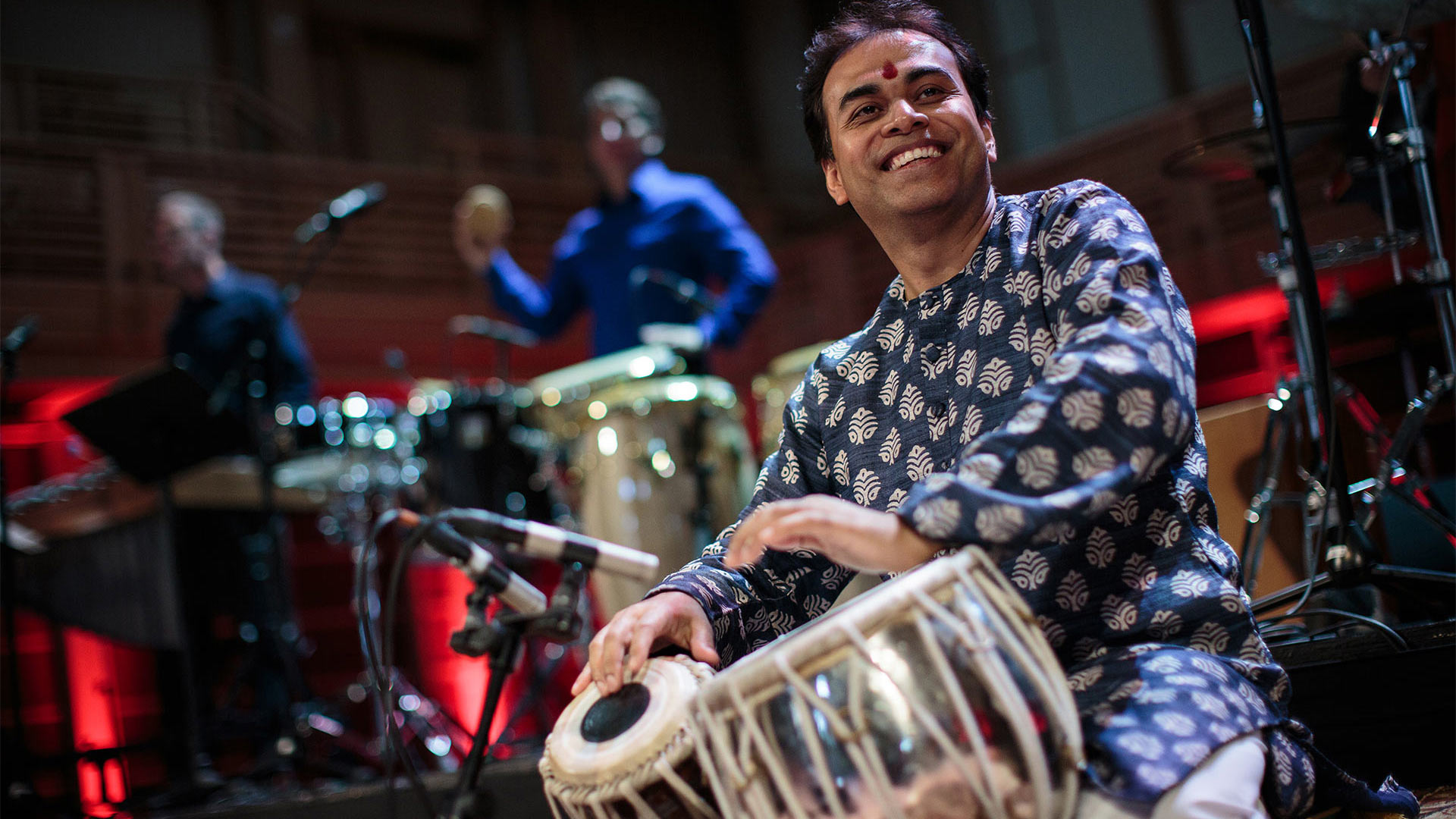 Sandeep Das on stage playing the tabla, a set of traditional Indian drums.