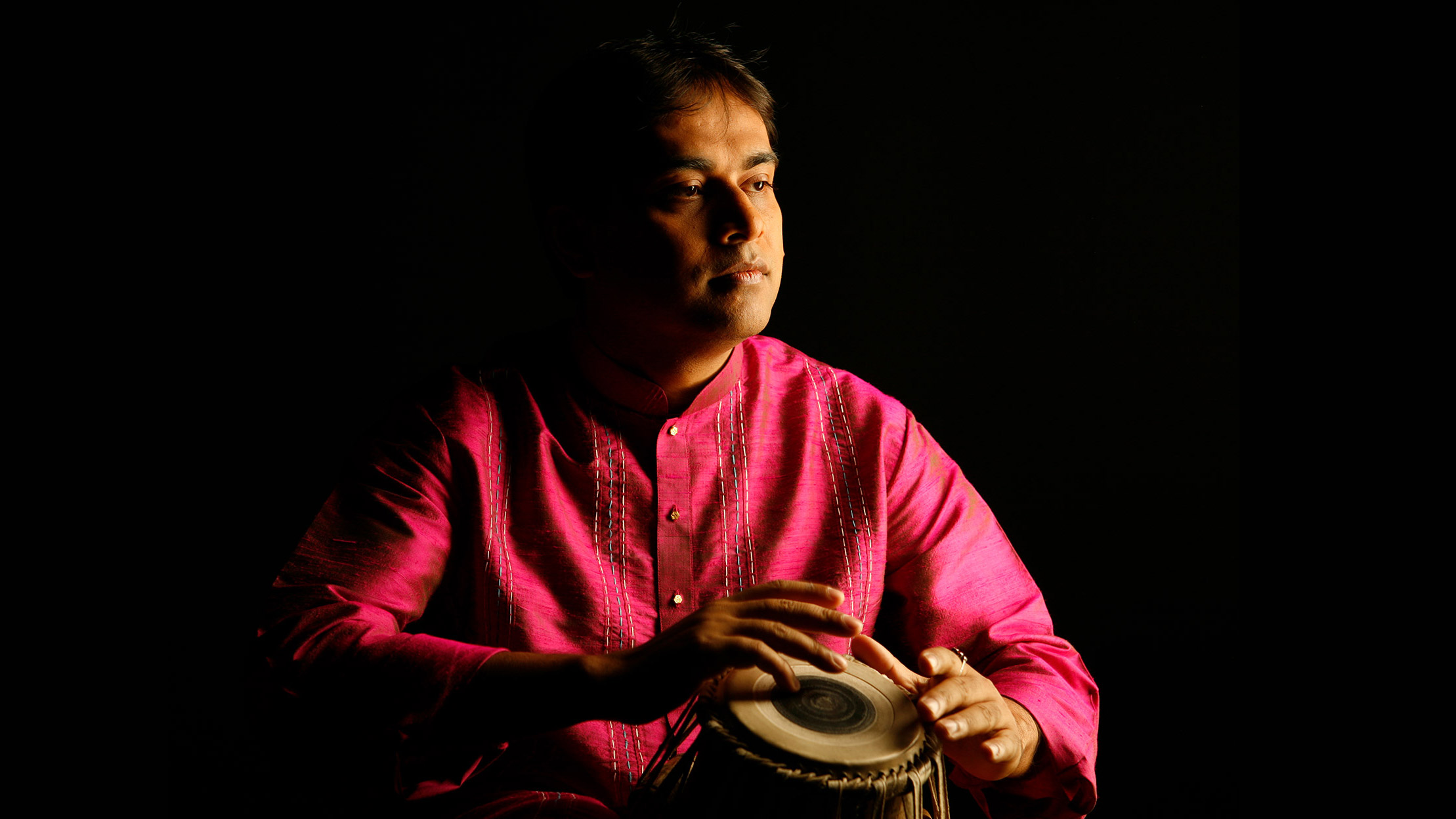 Sandeep Das with a black background playing the tabla.
