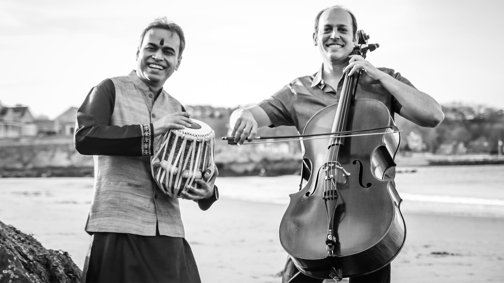 Grayscale image of Sandeep Das playing the tabla, an Indian drum, on the left and Mike Block playing the cello on the right.