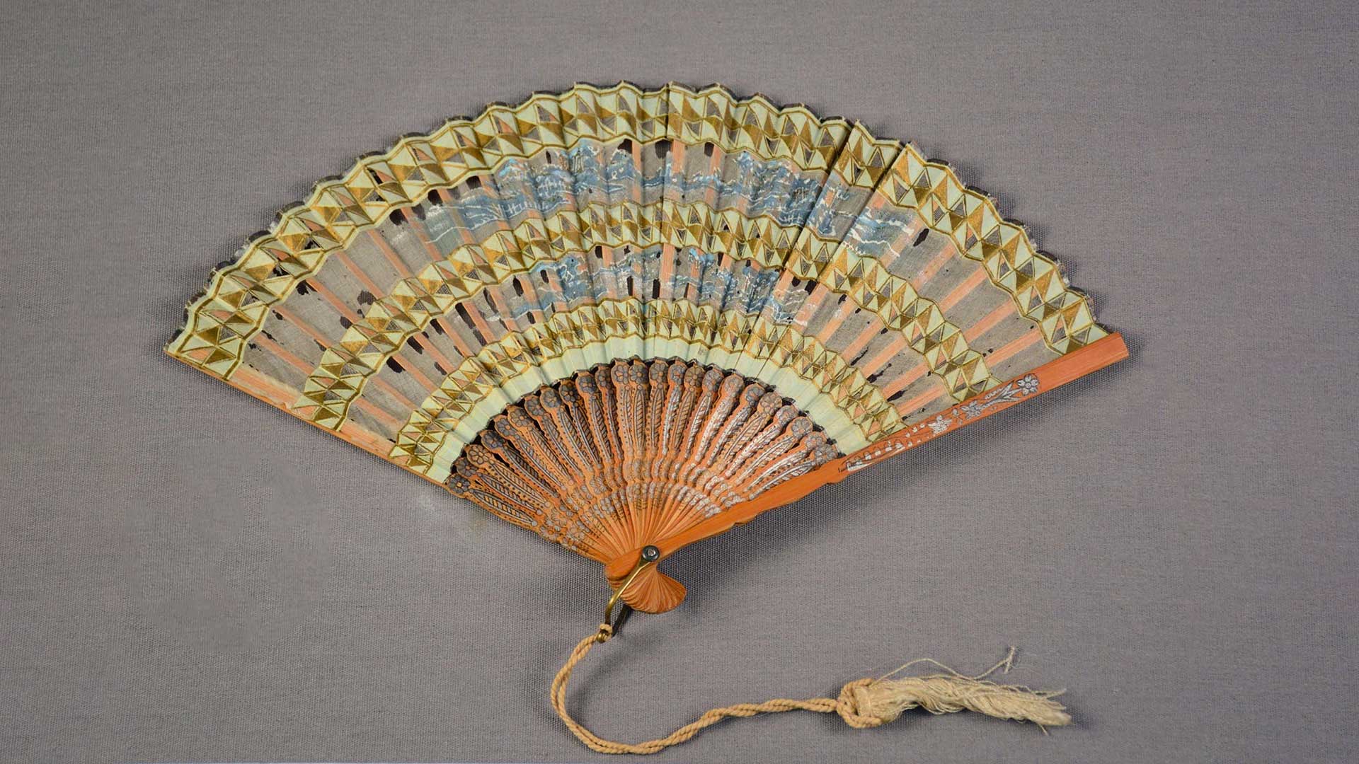 orange/yellow foldout fan with tassle and blue and brown geometric designs