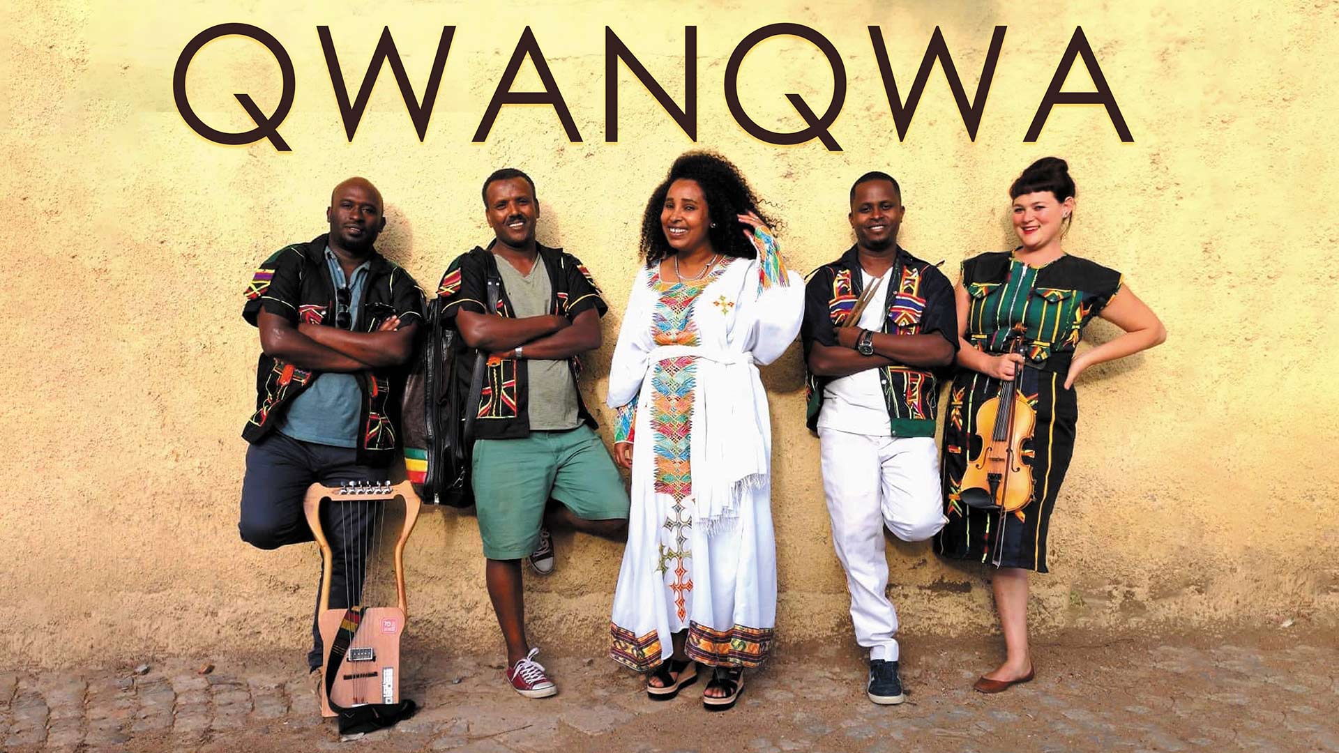 5 instrumentalists pose with instruments and contemporary African clothing in front of a yellow wall