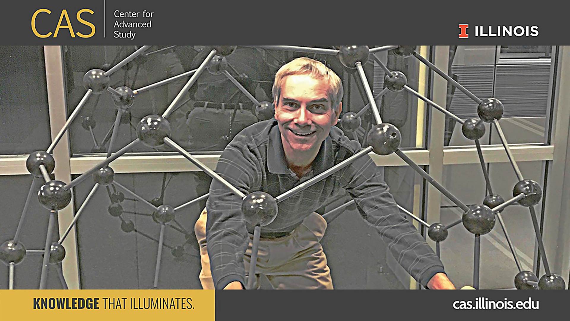 smiling man standing inside of a stick and ball dome model