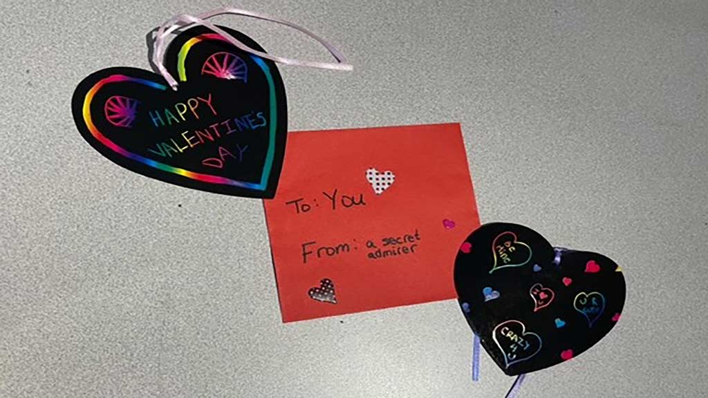 two heart-shaped cards lying on either side of a red valentine