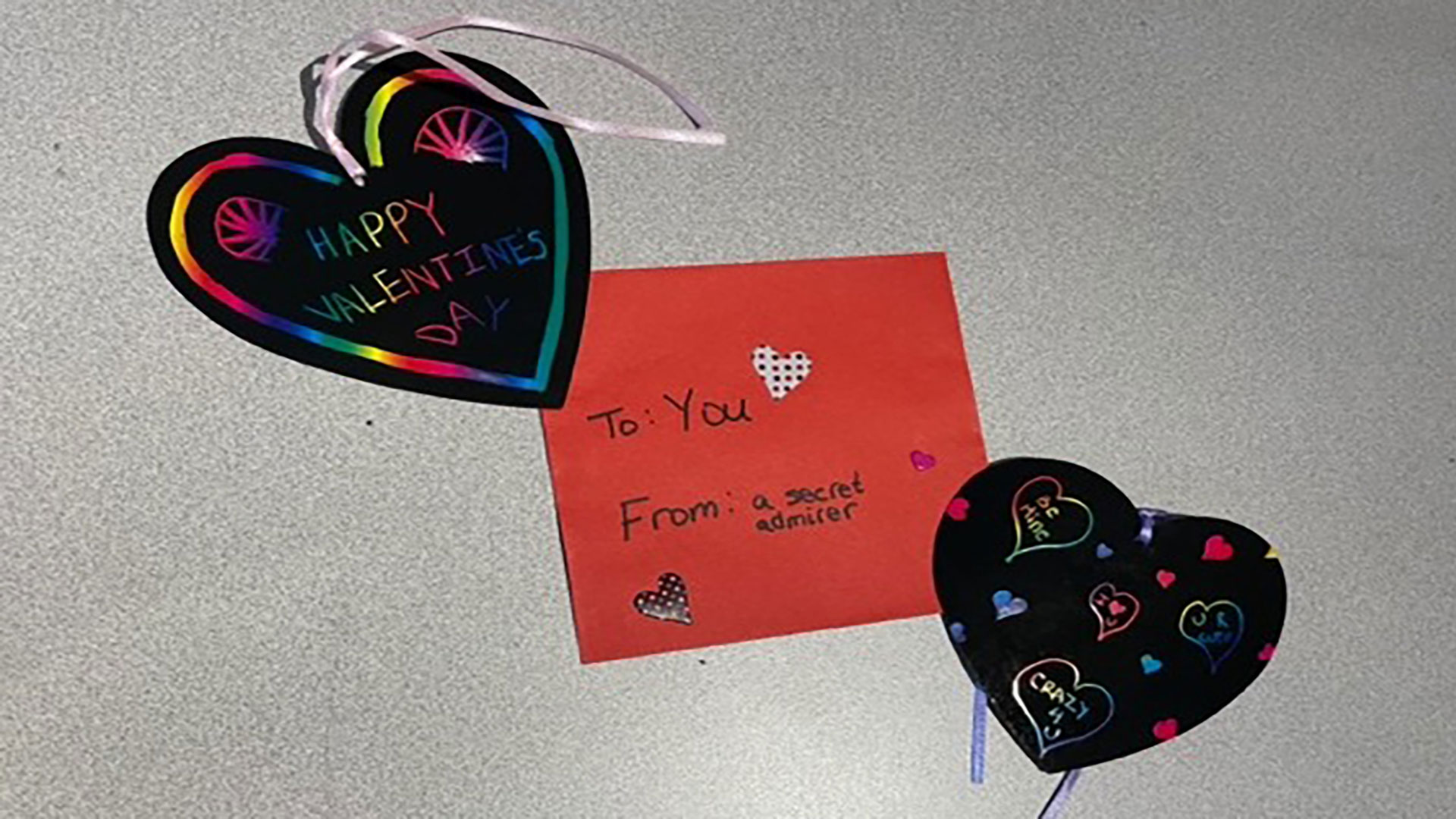 two heart-shaped cards lying on either side of a red valentine's day envelope