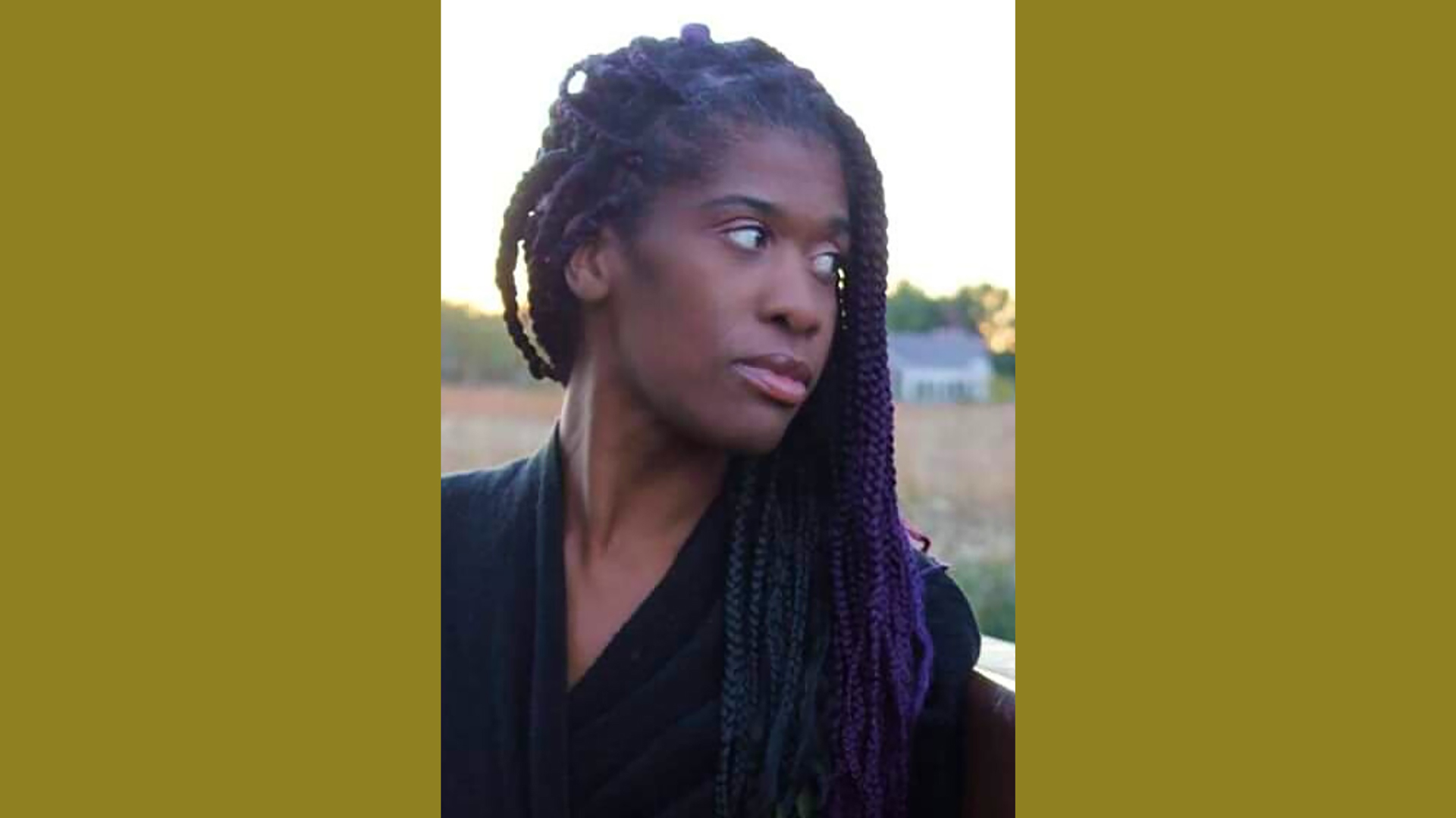 woman with purple braids looking to the right over her shoulder with trees in the background