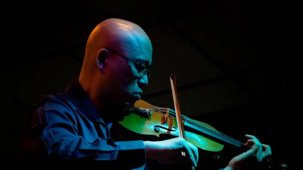 close-up of man playing the violin under blue ambient lighting