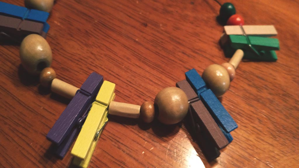 Closeup of handmade necklace made of different colored wooden beads and clothespins on a table