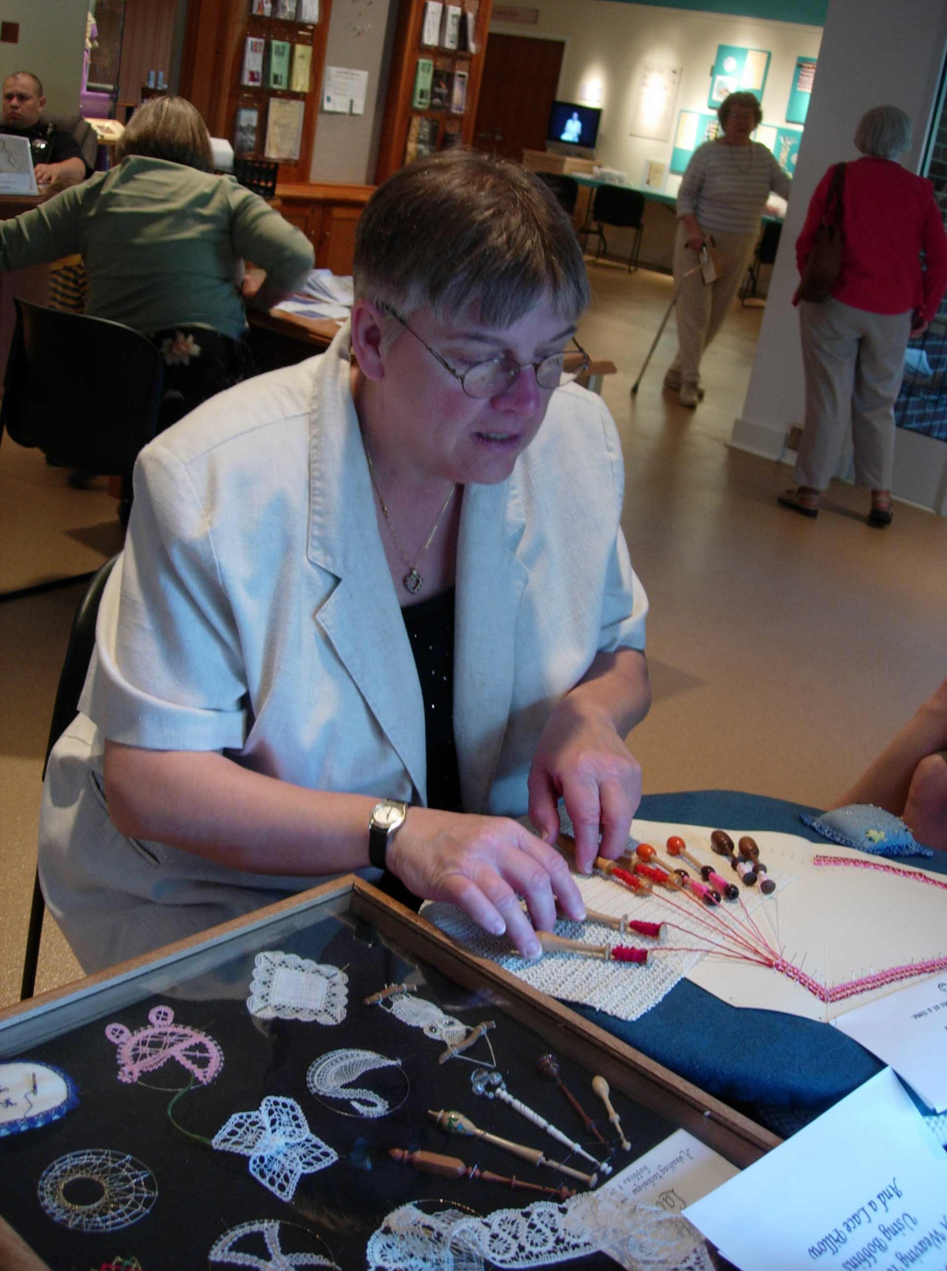 A woman wearing glasses sitting at a table with crafts 
