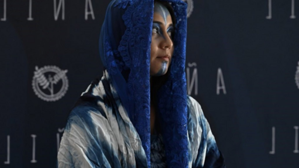 woman looking to the right wearing a blue headscarf and blue face paint