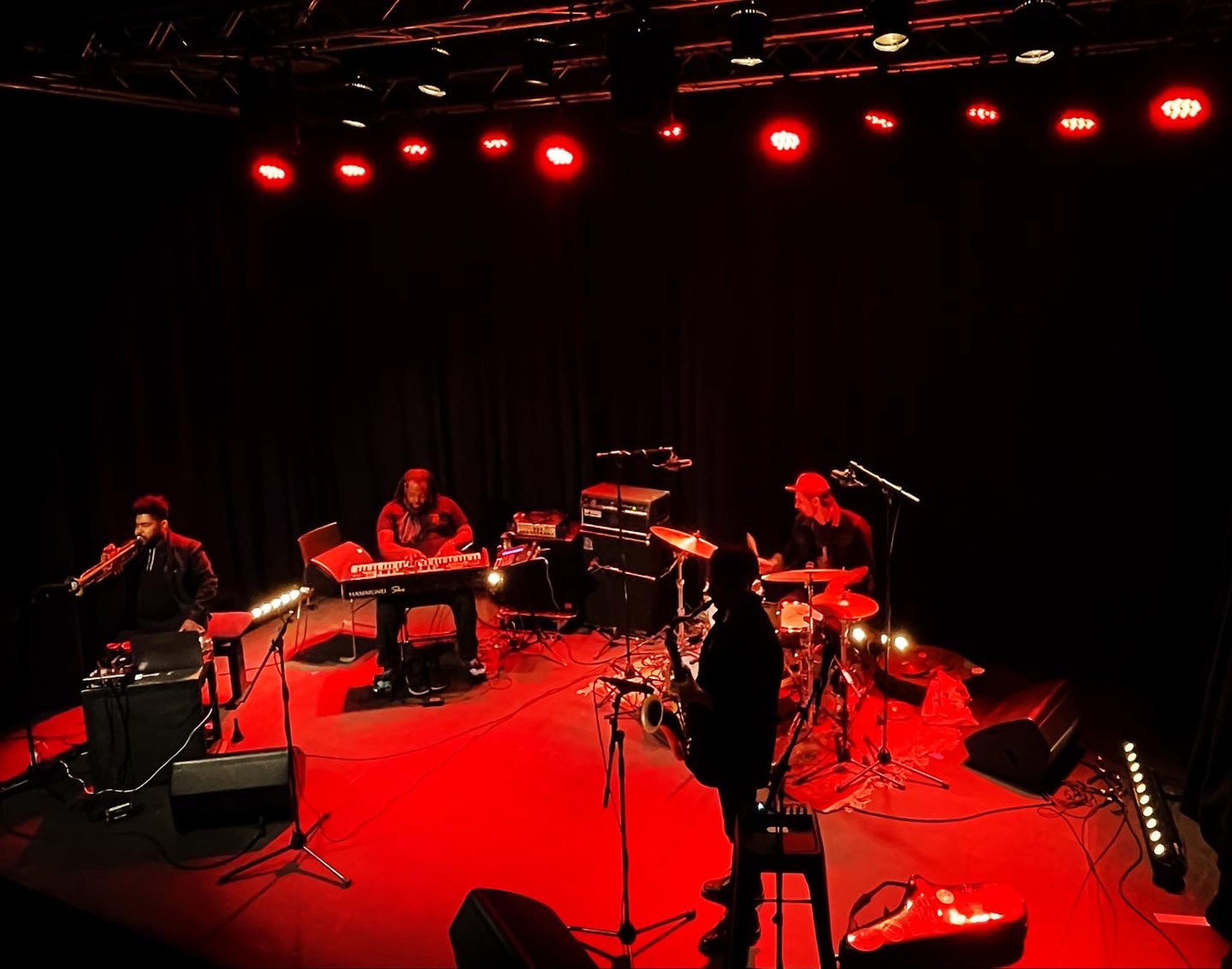 four musicians on stage with red lighting
